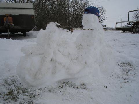 1989 Ford F-250 - A snowman shaped like a motorcycle sits in the snow, with a blue cap on its head.