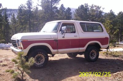 1979 Ford F-150 - This two-tone Ford Bronco is parked outdoors in a wooded area with mountains visible in the distance.