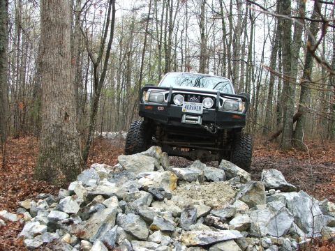 1996 Ford Bronco - Toyota 4Runner tackles a challenging rock obstacle in a wooded area.