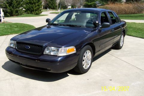 2003 Ford Crown Victoria - This dark blue 2003 Ford Crown Victoria is shown from a front 3/4 angle, parked on a concrete driveway.