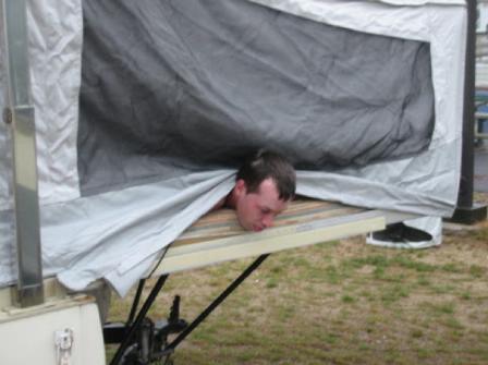 2001 Ford Crown Victoria - A person's head is visible as they poke out from under the fabric of a pop-up camper.