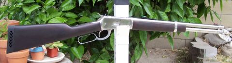 1990 Ford Bronco - A lever-action rifle with a dark wooden stock and a shiny metal barrel is displayed outdoors.