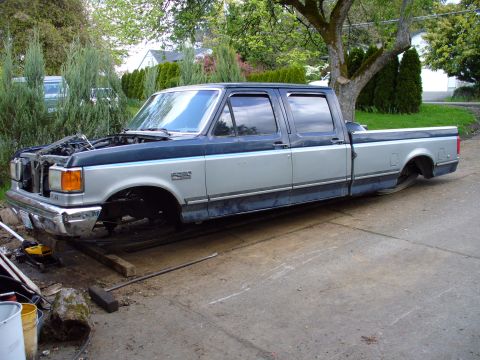 1978 Ford Bronco - This two-tone pickup truck, possibly a Ford F-series, is shown with its hood open and missing its wheels, resting on wooden blocks.