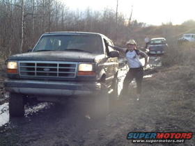 1996 Ford Bronco - A dark-colored Ford Bronco navigates a muddy off-road trail with other vehicles in the background.