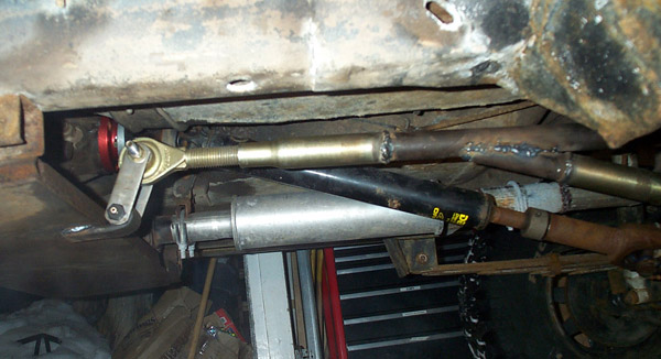 Vehicle undercarriage showing suspension linkage and exhaust pipe. Some welds are visible on metal tubing
