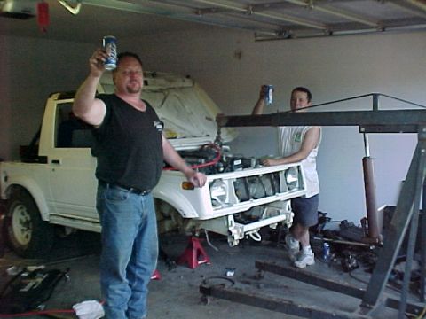 1978 Ford Bronco - Two men in a garage with a white SUV that has its front bumper removed and hood open.
