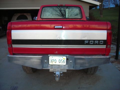 1995 Ford F-250 - The rear of a red Ford pickup truck is shown, a chrome bumper and a multi-colored tailgate stripe.