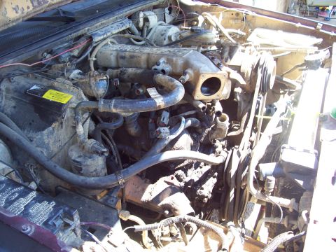 1989 Ford Bronco II - Close-up view of a dirty engine bay, showing various components and wiring.