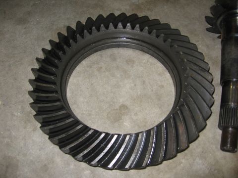 1974 Ford F-100 - Differential gears, a ring gear and pinion shaft, are shown in a close-up view on a concrete surface.