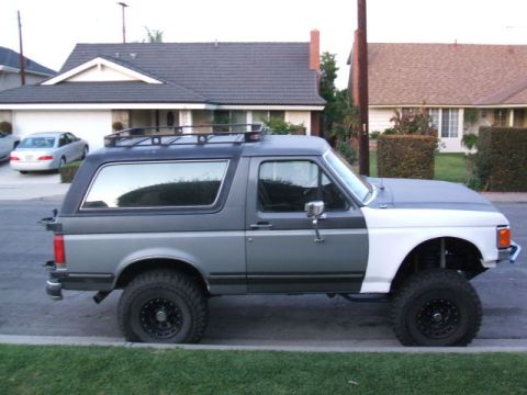 1988 Ford Bronco - This lifted 1988 Ford Bronco features a two-tone paint scheme and a roof rack.