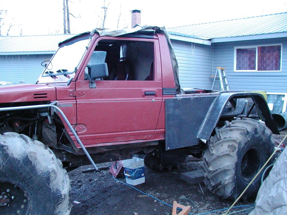 Red Suzuki Samurai with huge tires and custom bed