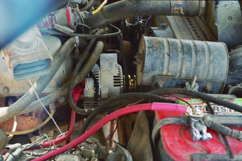 1978 Ford Bronco - Close-up view of engine components including the alternator and battery, with numerous wires and hoses visible.
