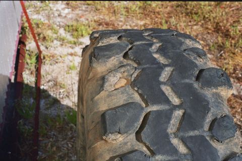 1978 Ford Bronco - A close-up view of a heavily used off-road tire shows its deep tread pattern and signs of wear.
