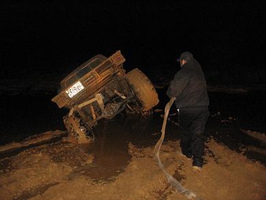 2005 Ford Excursion - A person attempts to help a stuck truck in the mud at night.