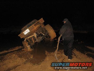 1987 Suzuki Samurai - A person attempts to help a 1987 Suzuki Samurai that is stuck in the mud at night.