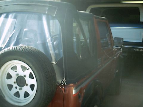 1978 Ford Bronco - An orange SUV is parked next to another vehicle, with a spare tire mounted on its rear.