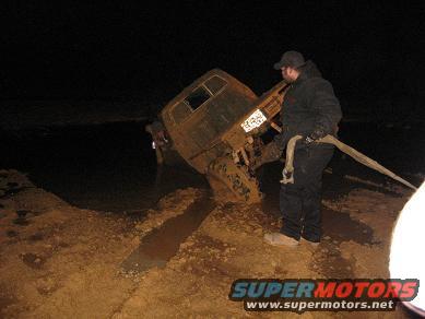 1987 Suzuki Samurai - A 1987 Suzuki Samurai is stuck in the mud and being pulled out with a tow strap.