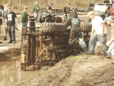 1987 Suzuki Samurai - A group of people watch as an off-road vehicle is stuck in a mud pit.