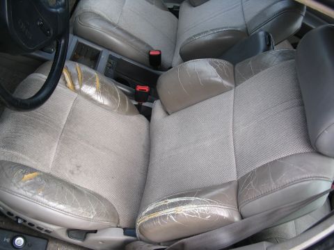 1993 Ford Taurus - The interior of the car shows significant wear on the seats, with torn leather and faded fabric.
