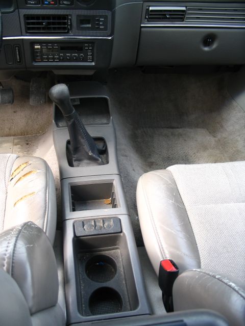 1993 Ford Taurus - The interior of a car shows a worn passenger seat and center console, with a visible radio and gear shifter.