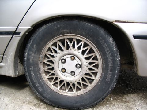 1993 Ford Taurus - Close-up of a silver wheel and tire on a silver car. The tire shows some text, but no year is discernible.