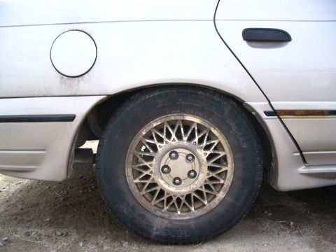 1993 Ford Taurus - Close-up of a car's rear wheel and fender, with a gas cap door visible.