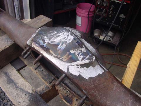 1979 Ford Bronco - Metal axle housing with visible weld repairs, resting on wooden blocks.