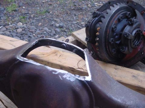 1979 Ford Bronco - A differential housing with a cut-out section sits next to a differential gear assembly on wooden planks.