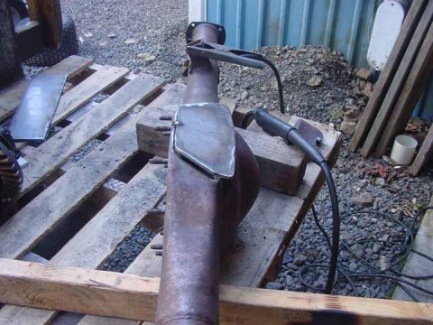 1979 Ford Bronco - A rear axle housing is being worked on with welding equipment, resting on wooden pallets outdoors.