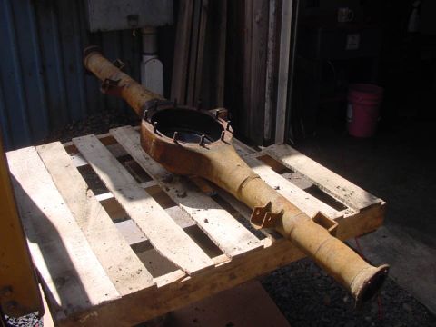 1979 Ford Bronco - This rusty rear axle housing is resting on a wooden pallet outdoors.