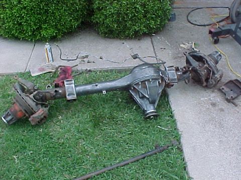 1978 Ford Bronco - A disassembled rear axle assembly, likely from a Ford Bronco, lies on the ground.