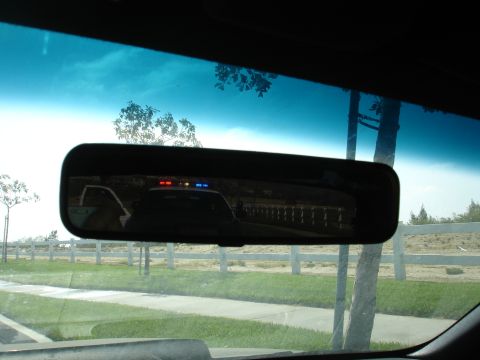 1993 Ford Taurus - Reflection of a police car with illuminated red and blue lights is visible in the rearview mirror.