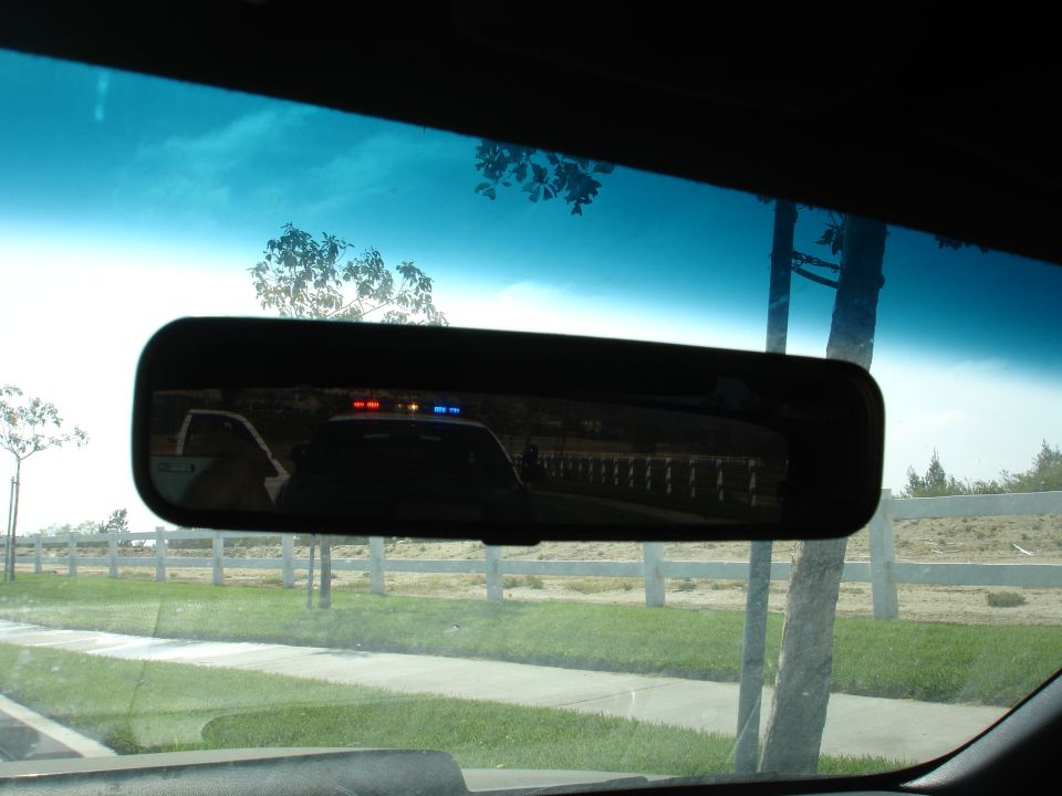 Reflection of police car with red and blue lights in rearview mirror
