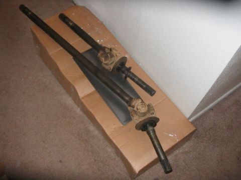 1991 Ford Bronco - Two Dana 60 front axle shafts with U-joints are shown, laid out on a piece of cardboard.