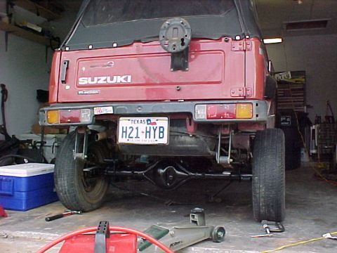 1978 Ford Bronco - The rear of a red Suzuki Samurai is shown, with its license plate and spare tire mount clearly visible.