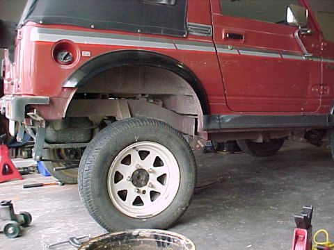 1978 Ford Bronco - A red SUV, possibly a Suzuki Samurai, is shown from the side with its front wheel removed and suspension components visible.