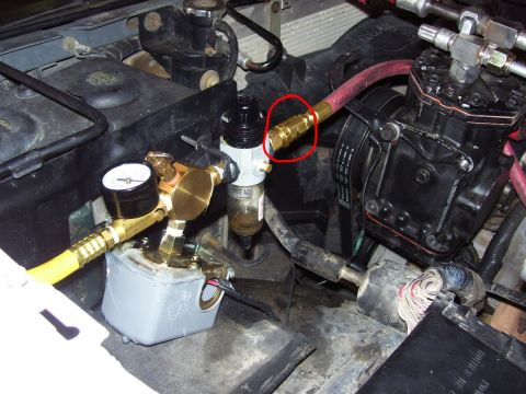 1992 Ford Bronco - Close-up view of an engine compartment, focusing on an air compressor system with a regulator and pressure gauge. A red circle draws attent…