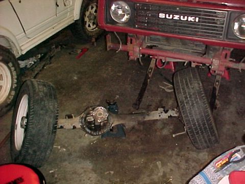 1978 Ford Bronco - Suzuki Samurai front end and axle assembly in a workshop setting. Another vehicle is partially visible.
