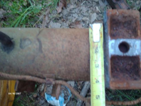1990 Ford F-150 - A close-up view of a rusty metal pipe, with a yellow measuring tape indicating its diameter.