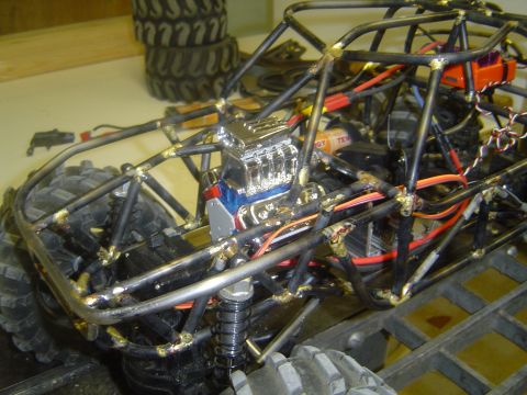 1993 Ford Bronco - A custom-built off-road buggy is shown, a chrome engine and extensive roll cage construction. Tires are visible in the background.