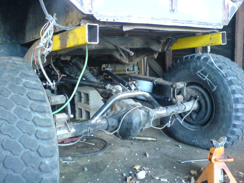 1975 Jeep CJ5 rear axle and suspension with large tires, yellow frame supports, and visible wiring