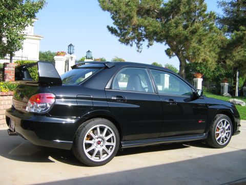2007 Subaru Impreza - A black 2007 Subaru Impreza WRX STI sedan is parked in a driveway on a sunny day.