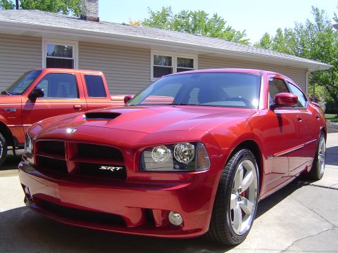 2006 Dodge Charger - A red 2006 Dodge Charger SRT is parked in front of a house, with a red pickup truck to its left.