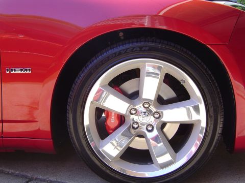 2006 Dodge Charger - Close-up of a red 2006 Dodge Charger's front fender, the HEMI badge and a polished chrome wheel with red brake calipers.