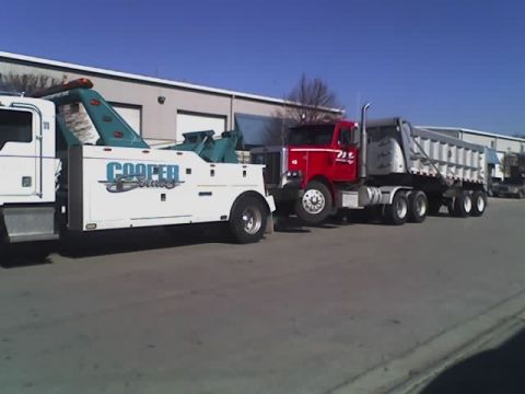 1992 Ford Bronco - A tow truck is parked next to a red dump truck tractor and trailer combination.