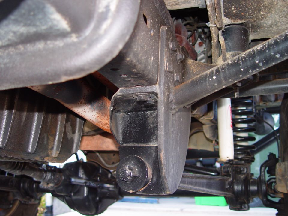 Underside of truck showing frame bracket, coil spring, white shock and driveshaft