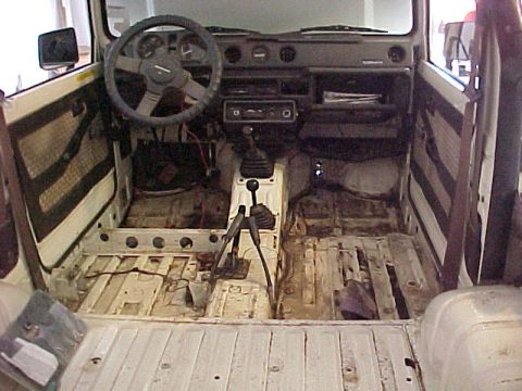 1978 Ford Bronco - The interior of a vehicle is shown with its floor stripped bare, revealing the chassis and transmission components.