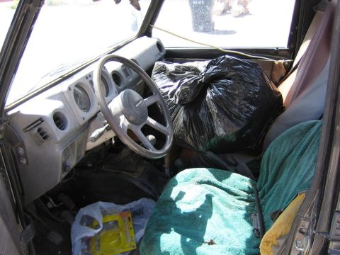 1987 Suzuki Samurai - Interior view of a 1987 Suzuki Samurai, filled with items and covered in blankets.