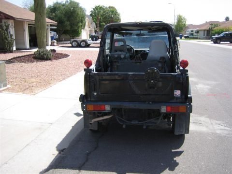 1987 Suzuki Samurai - Rear view of a black 1987 Suzuki Samurai with its soft top removed, parked on a suburban street.