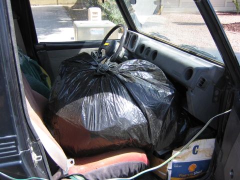 1987 Suzuki Samurai - The interior of a vehicle is filled with a large black trash bag, obscuring the passenger seat.